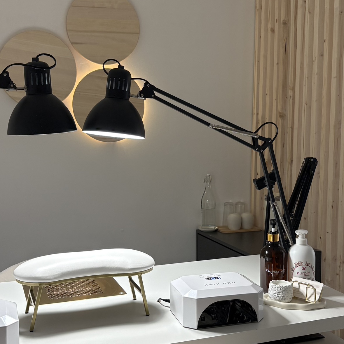 Le poste de travail du studio : lampes articulées, repose-main, lampe UV et produits.
